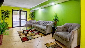 A reception area with a green wall, two sofas, a glass coffee table, and a patterned rug. - Quality Inn & Suites near Six Flags East (Atlanta)