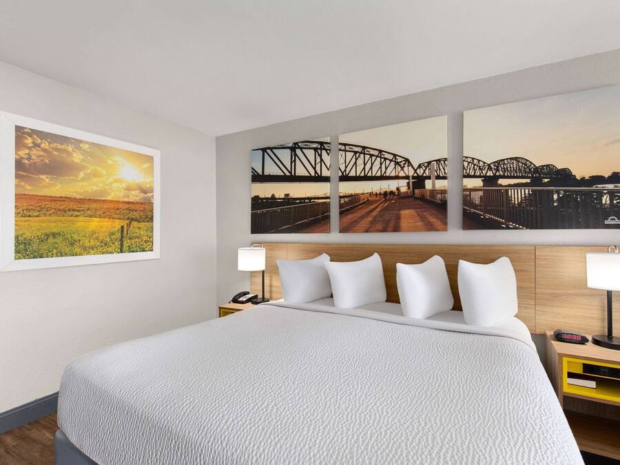 A hotel room with a large bed, two bedside tables, a nightstand, and three framed photographs on the wall.