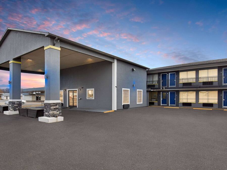 A modern building with a covered parking area and a two-story structure with multiple doors.