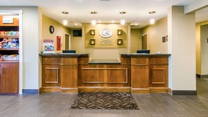 A reception area with a wooden reception desk, a clock, and a sign for Comfort Suites. - Comfort Suites Wytheville near Conference Center (Wytheville)