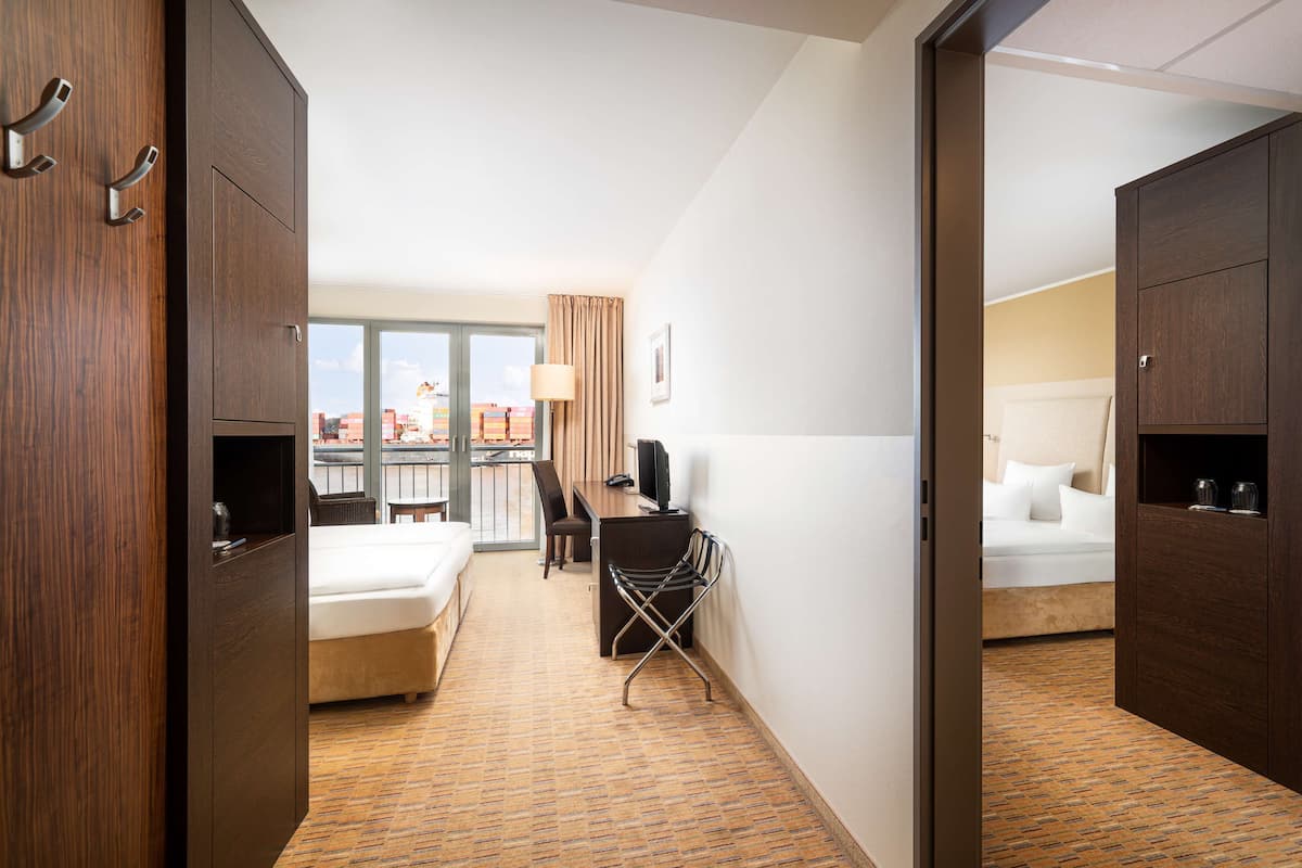 A hotel room with a bed, a desk, a chair, and a view of the city.