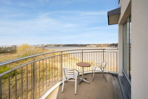 Un balcon donnant sur une rivière et sur des bâtiments situés au loin.