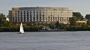 Un hôtel moderne, doté d’un grand bâtiment, offrant une vue sur le front de mer et où l’on peut admirer un voilier sur l’eau.
