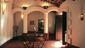 A dining area with a round table and chairs, a fan, and a vase with flowers. - Hotel Laguna Anjuna, Goa (Anjuna)