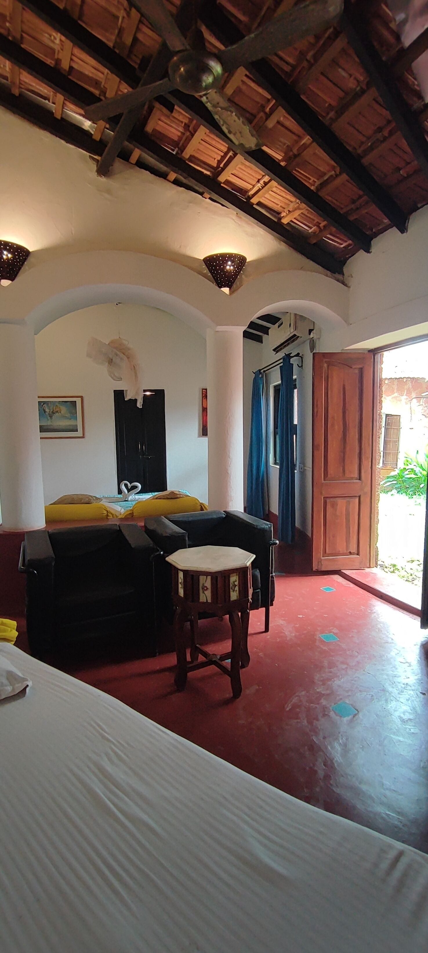 A room with a bed, a small table, and a doorway leading outside.
