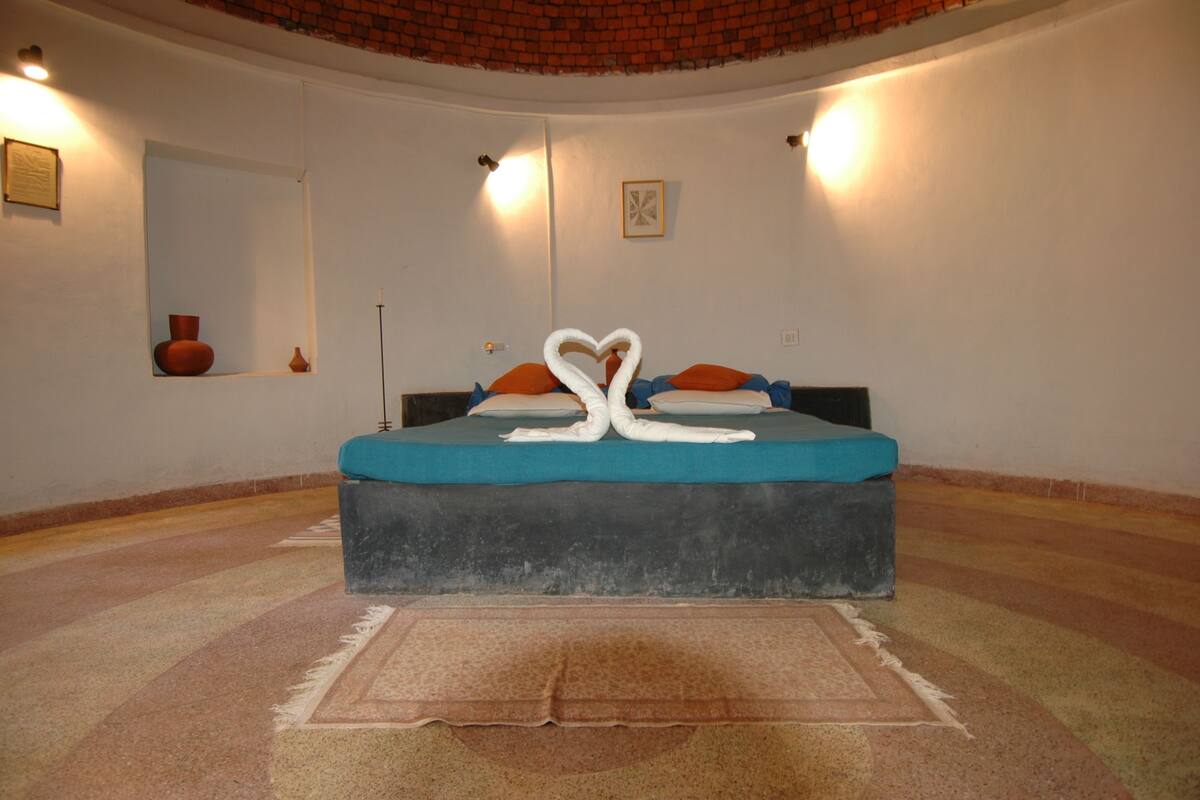 A bedroom with a bed, a rug, a mirror, and wall-mounted lights.