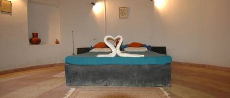 Un dormitorio con cama, alfombra, espejo e iluminación en la pared.