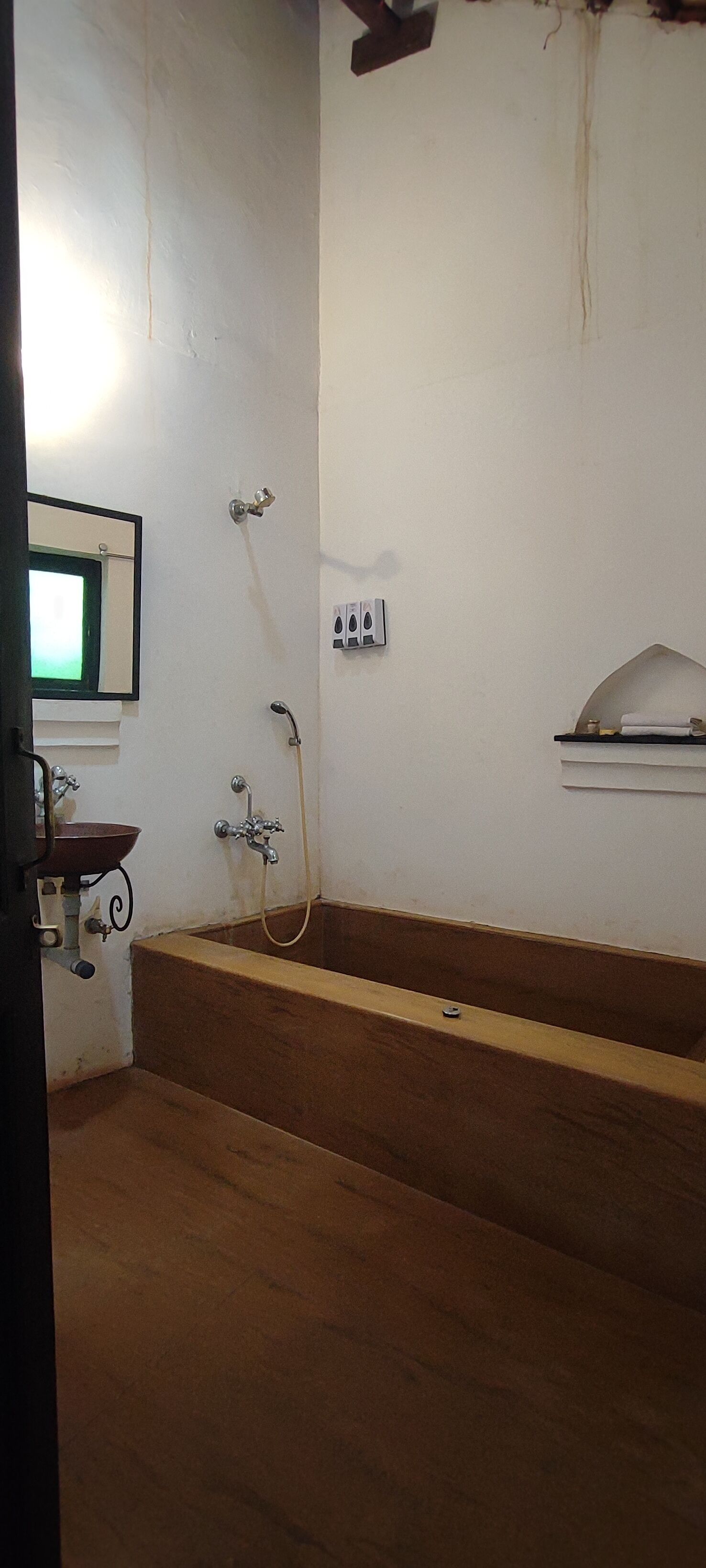 A bathroom with a sink, mirror, shower, and a towel rack.