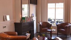 A living room with leather armchairs, a fireplace, a large mirror, and a chandelier. - Hotel Clemens Amsterdam (Amsterdam)
