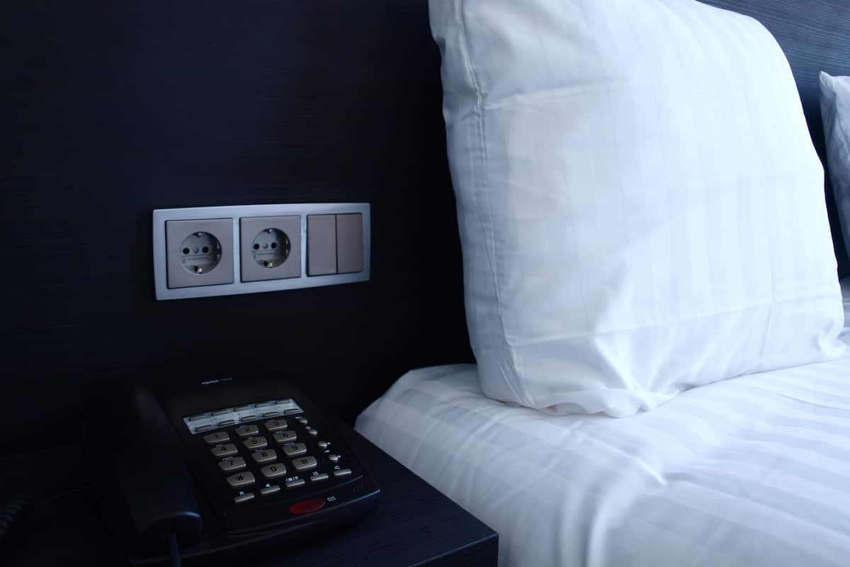 A hotel room with a bed, a nightstand, and a phone.