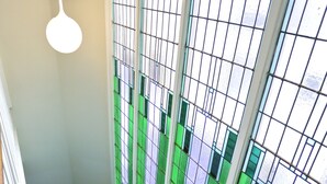 Una escalera con barandilla de madera, pared blanca y ventana con vidrio esmerilado.