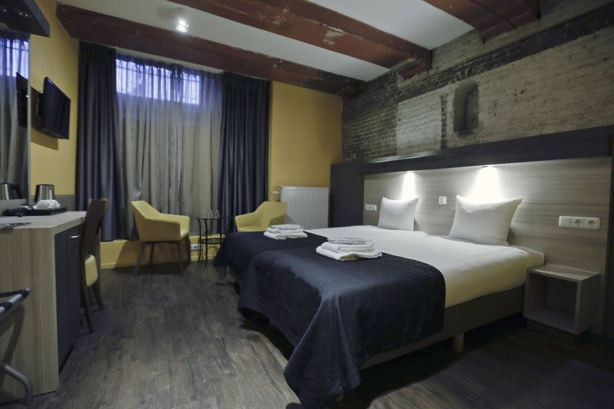 Una habitación de hotel con cama, mesitas de noche, escritorio, silla y televisión.