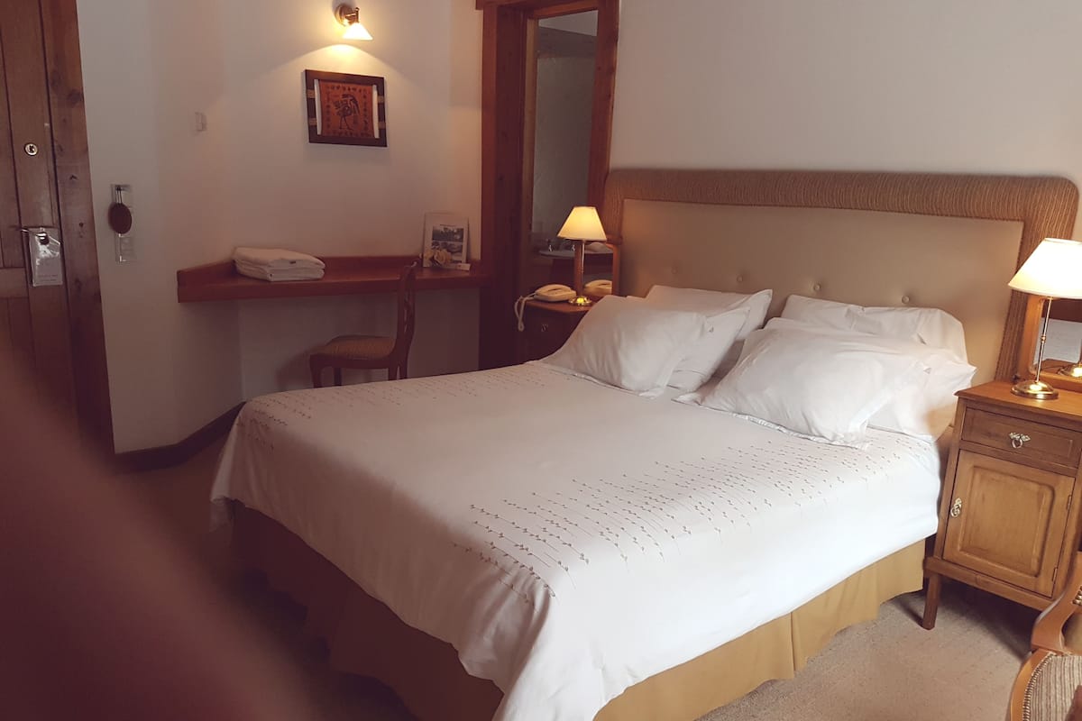 Une chambre d’hôtel avec un grand lit, des tables de chevet, un bureau et une chaise.