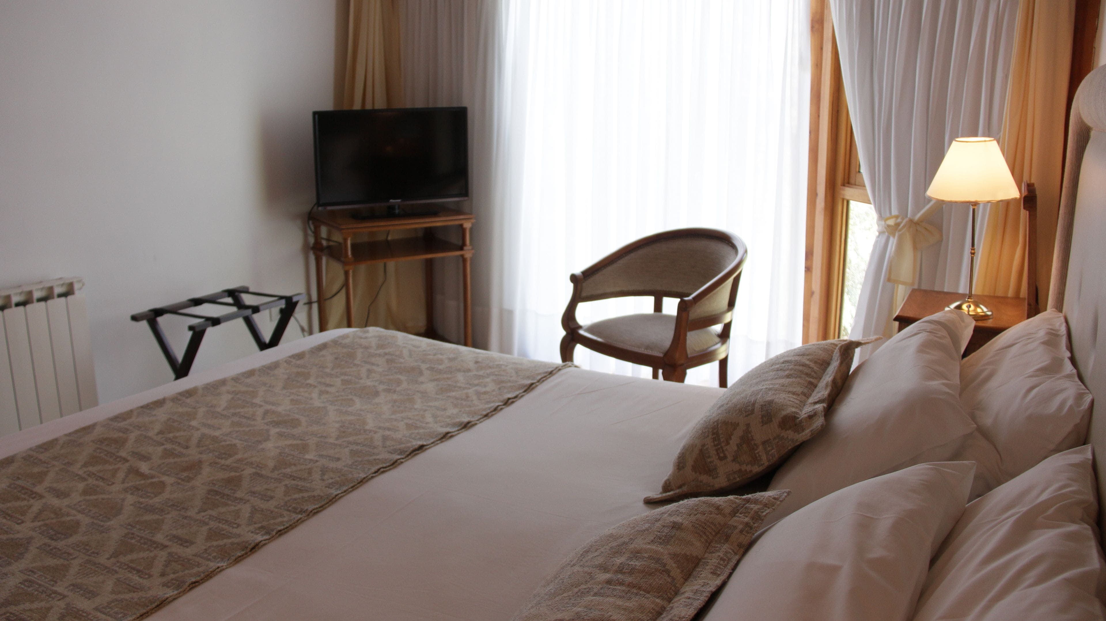 Une chambre d’hôtel avec un lit, une chaise, une télévision et une lampe.