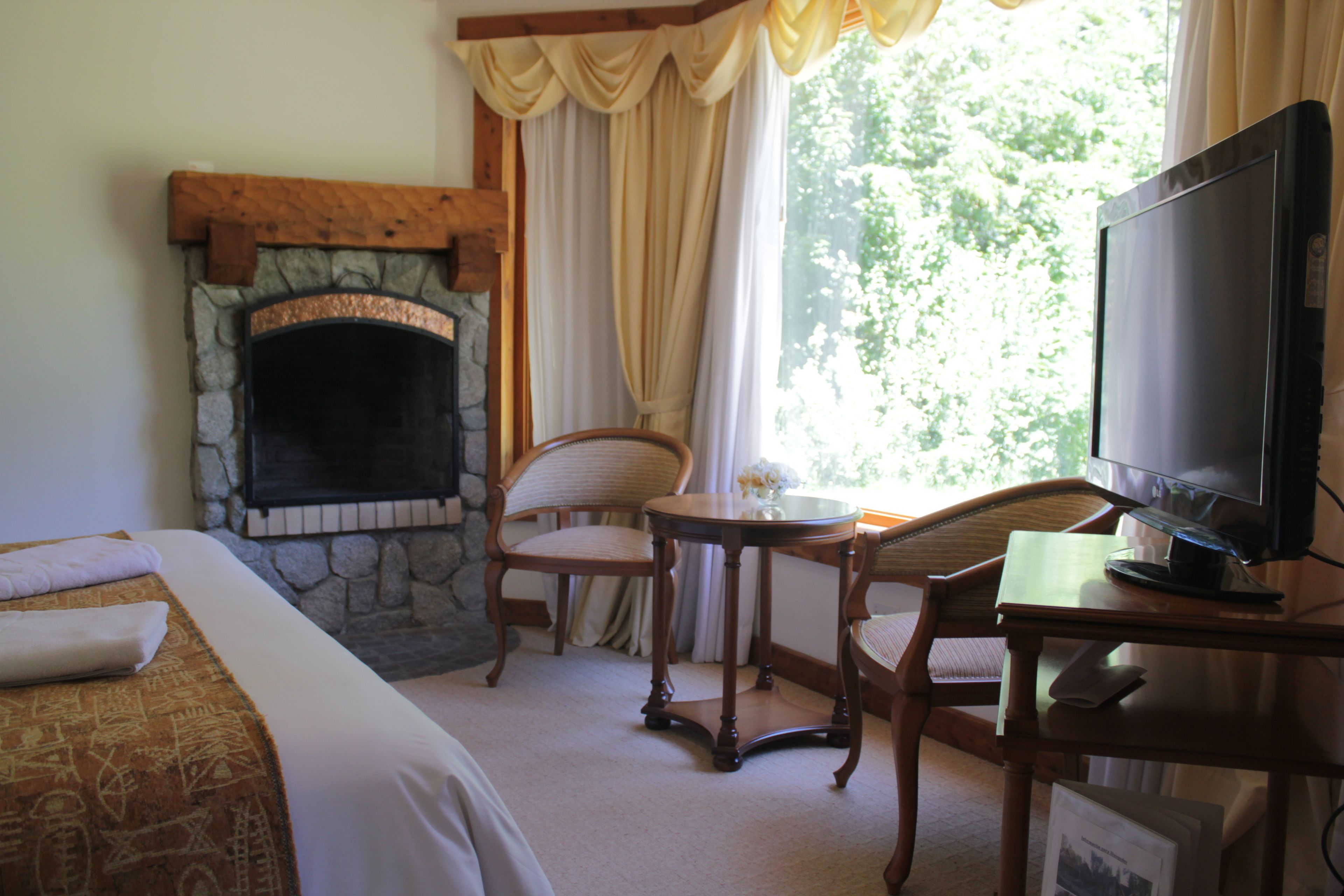 Une chambre d’hôtel dotée d’une cheminée en pierre, d’une télévision, d’une table à manger et d’un coin salon confortable.