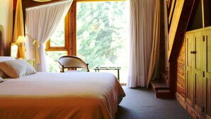 Een slaapkamer met een groot bed, een stoel en een houten garderobe.