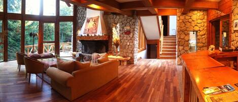 A cozy living room with a fireplace, wooden furniture, and a stone wall.