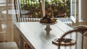 A dining table with a bowl of fruit and a bowl of nuts, a wooden chair, and a bench. - Hôtel Arvor Saint Georges (Paris)