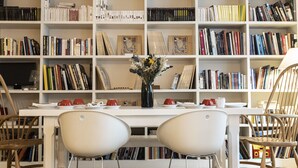 A library with bookshelves, a table with chairs, and a vase with flowers. - Hôtel Arvor Saint Georges (Paris)
