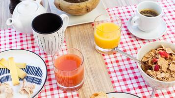 A breakfast table with a croissant, cereal, juice, and a small plant.