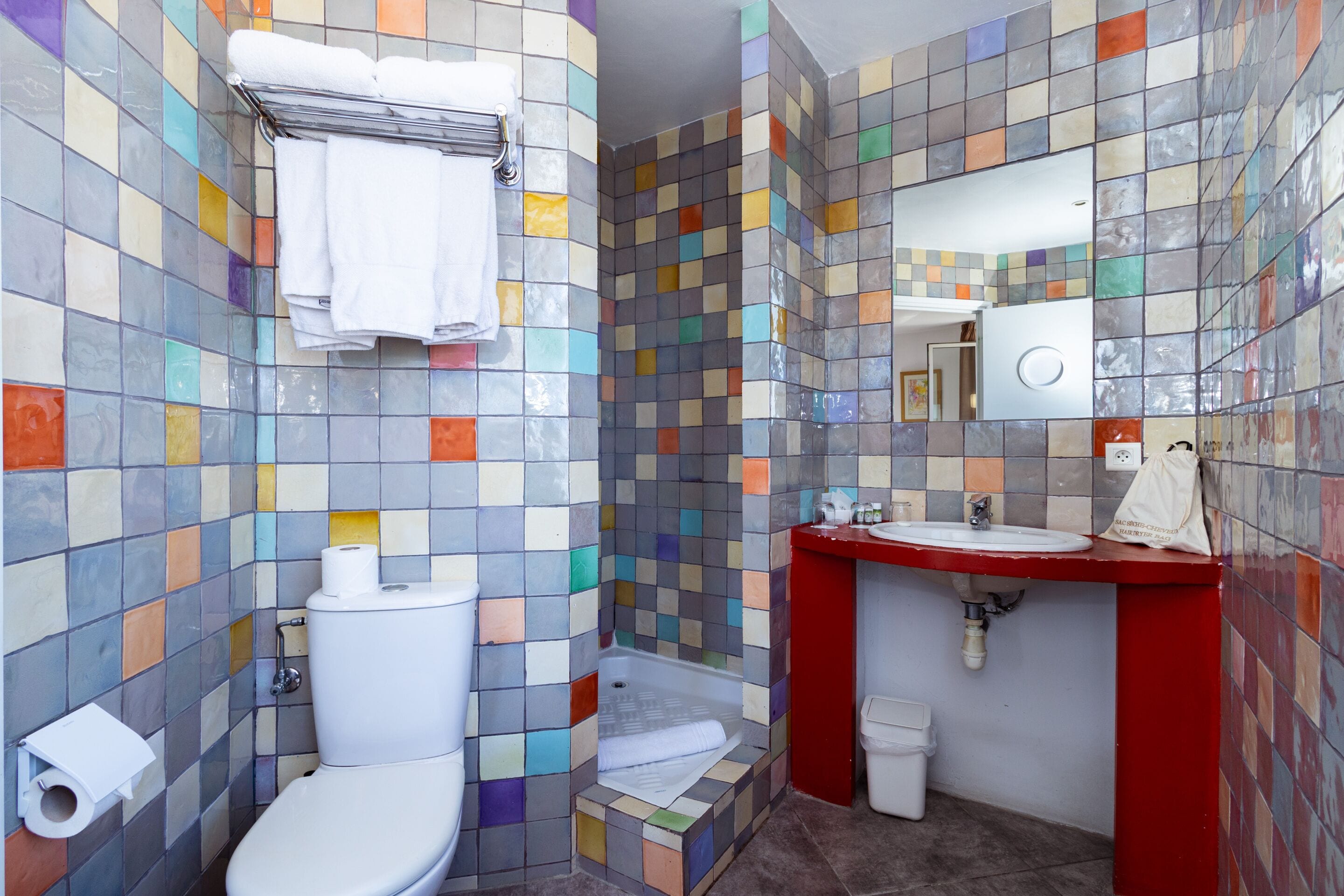 A bathroom with a toilet, a sink, a mirror, and a shower area.