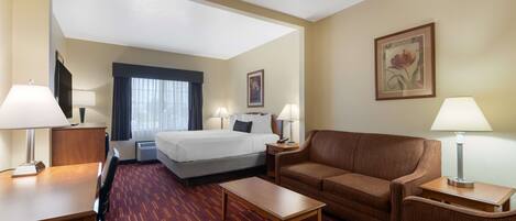 Une chambre d’hôtel avec un lit, un canapé, un bureau et une chaise.