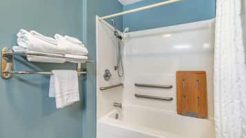 A bathroom with a bathtub, a towel rack with folded towels, and a shower head.
