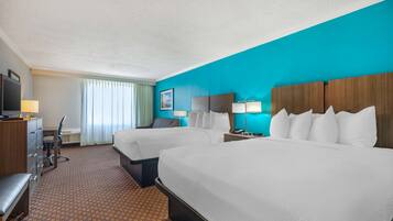 A hotel room with two beds, a desk, a chair, and a television.