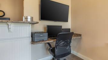 Een werkplek aan huis met een flatscreen televisie, een printer en een stoel.