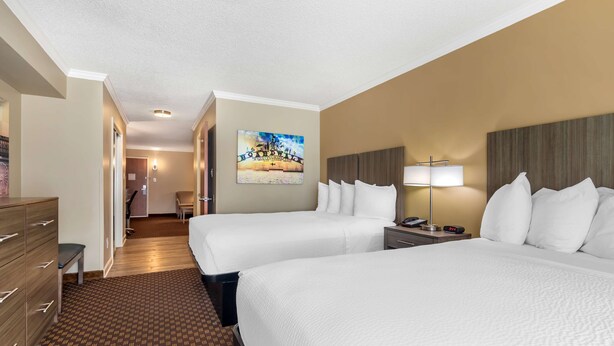 A hotel room with two beds, a desk, a chair, a lamp, and a painting on the wall. - Best Western Ocean City Hotel & Suites (Ocean City)