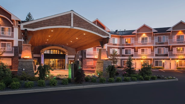 A multi-story hotel with a covered entrance, stone facade, and balconies. - Holiday Inn Express & Suites Interstate 90 by IHG (Coeur d'Alene)