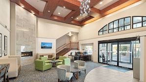 A spacious lobby with a fireplace, comfortable seating, a staircase, and large windows. - Holiday Inn Express & Suites Interstate 90 by IHG (Coeur d'Alene)