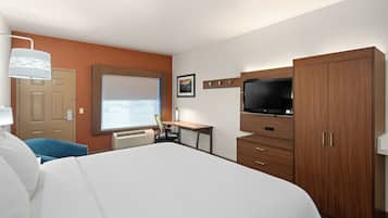 A hotel room with a large bed, a desk, a television, and a wardrobe.