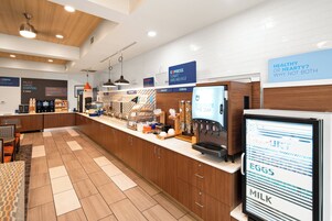 A modern cafe with a coffee bar, breakfast options, and a digital menu display.