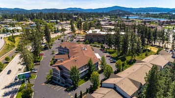A Holiday Inn Express & Suites with a parking lot, surrounded by trees and a mountainous backdrop.