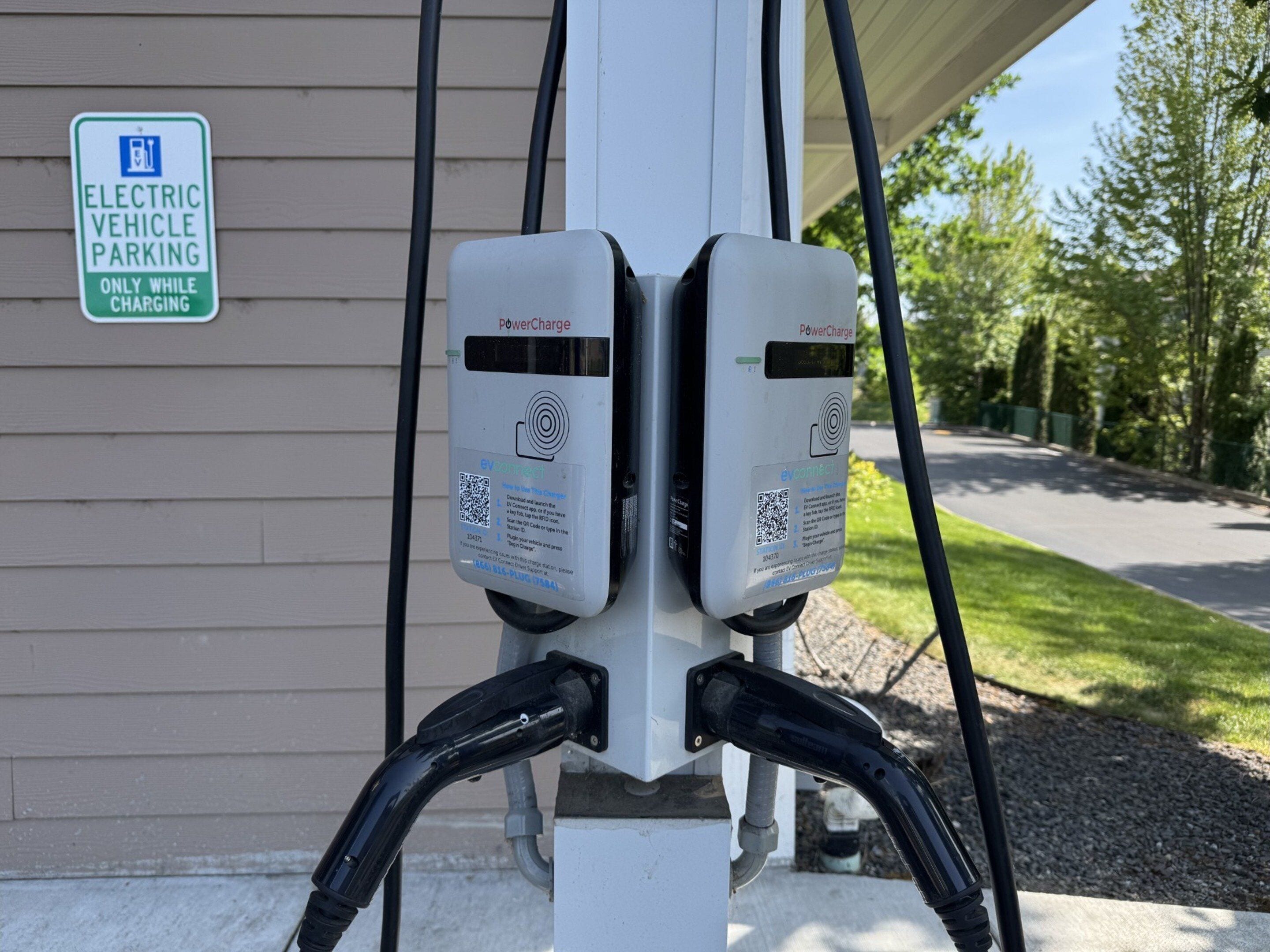 An electric vehicle charging station with a sign indicating it's for electric vehicle parking only while charging.