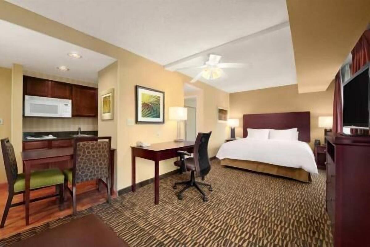 Une chambre d’hôtel équipée d’un lit, d’un bureau, d’une chaise, d’un four à micro-ondes et d’œuvres d’art.