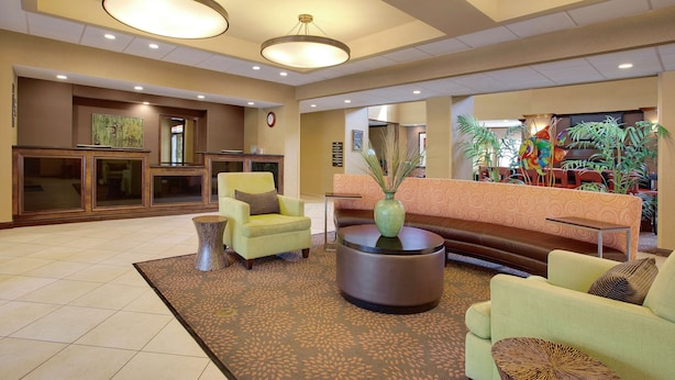 Un vestíbulo con mostrador de recepción, zona de estar y plantas decorativas.
