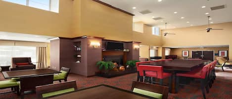 A hotel lobby with a fireplace, seating area, and a conference table.