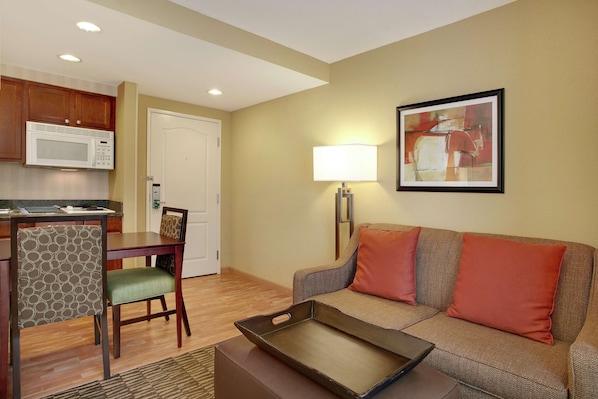 A compact living space with a kitchenette, a dining area, and a seating area with a couch and a lamp.