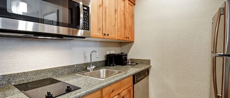 A kitchen with wooden cabinets, a stainless steel microwave, a dishwasher, and a granite countertop.