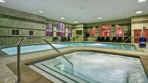 Une piscine intérieure dotée d’un plongeoir, de chaises longues et d’un panneau indiquant qu’il est interdit de plonger.