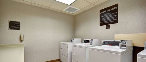 A hotel laundry room with a sink, three washers, and a sign indicating guest use only.