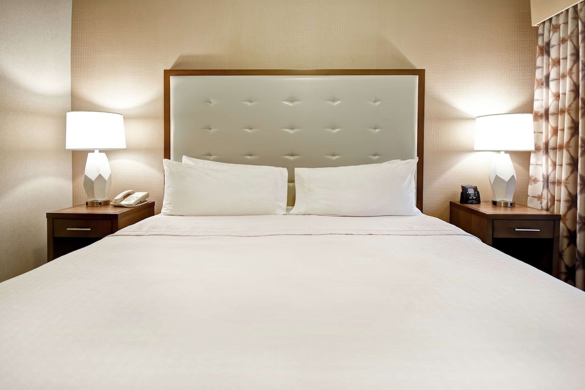 Een hotelkamer met een groot bed, twee nachtkastjes en twee lampen.