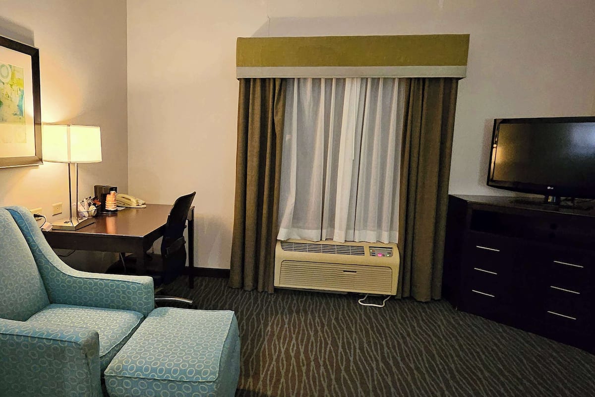 Habitación de hotel con una cama individual, un escritorio con silla, televisión y aire acondicionado.