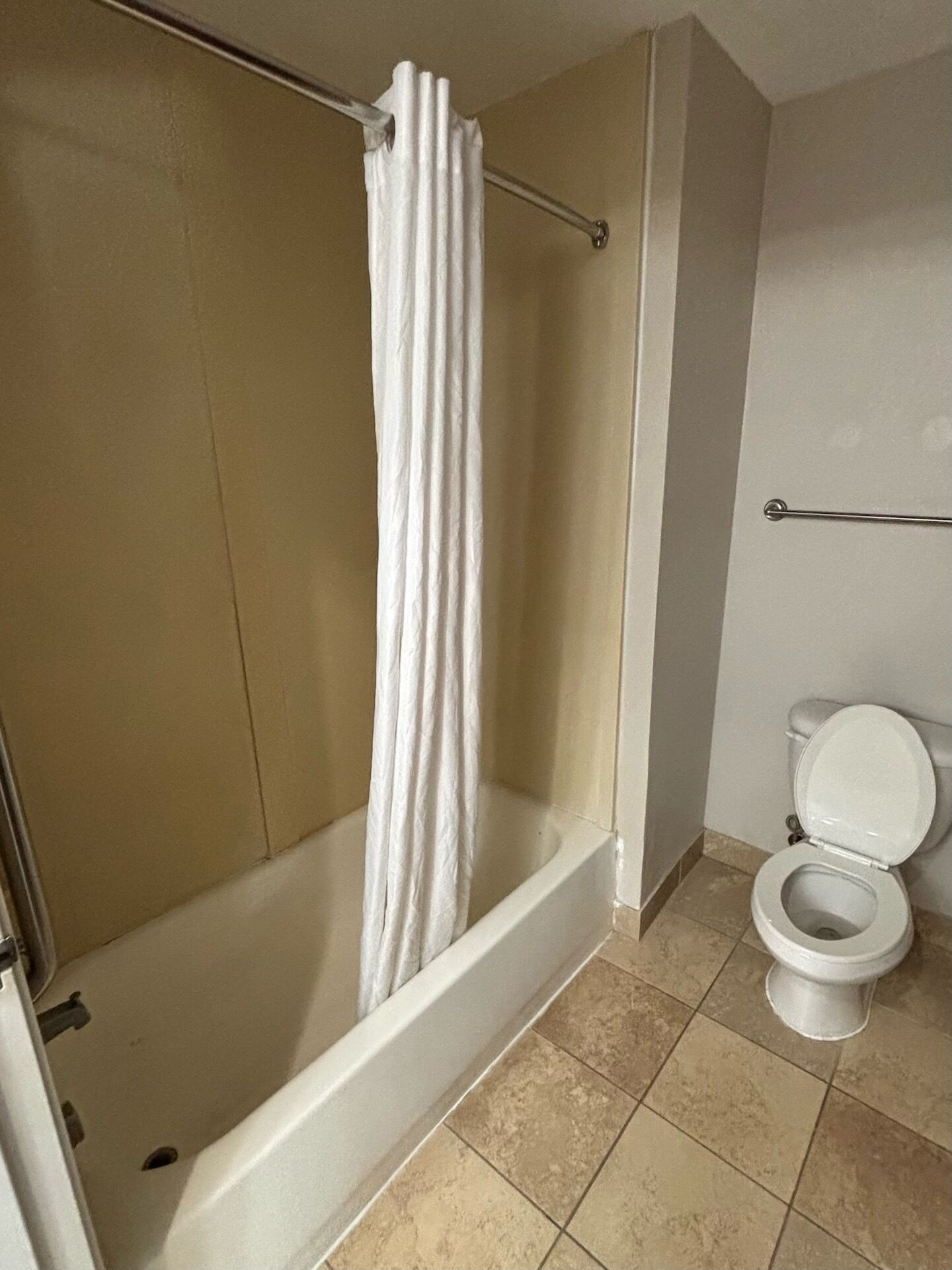 A bathroom with a bathtub, a shower curtain, and a toilet.