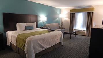 Une chambre d’hôtel avec un grand lit, un canapé, un bureau et une lampe.