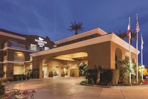 Um hotel com uma entrada ampla, vários andares e uma placa com a inscrição 'Homewood Suites'.