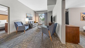Hotelkamer met een bed, twee sofa's, een televisie, een bureau en een raam met uitzicht.