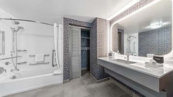 Un baño moderno con bañera, ducha, tocador y un espejo grande.